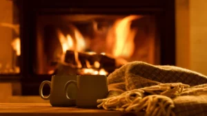 mugs of hot chocolate and a blanket in front of a cozy fire